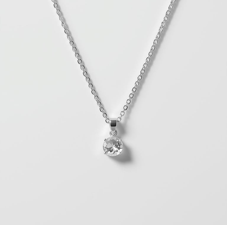 Elegant silver necklace featuring a round solitaire diamond pendant on a delicate chain.