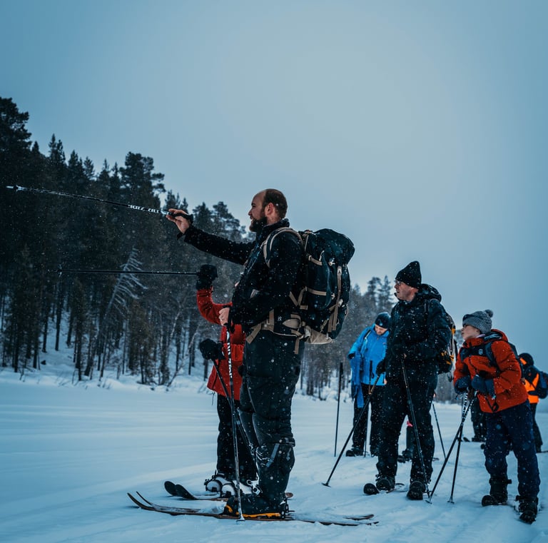 A group of hikers on a guided winter backcountry ski tour through a snowy forest landscape.