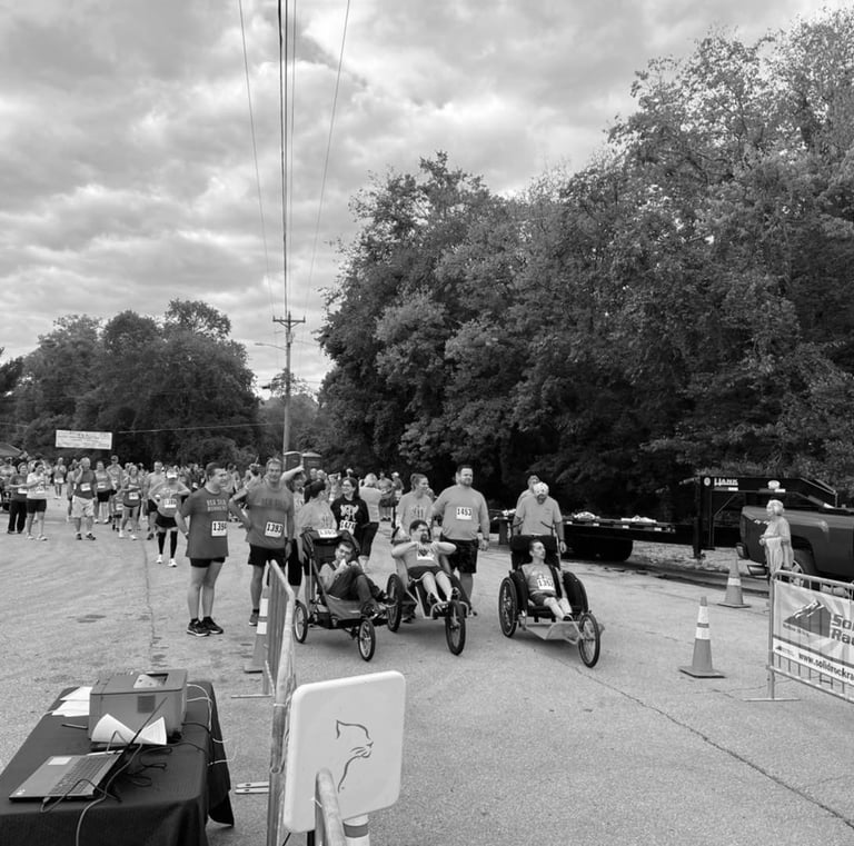 Black and White photo of Ainsley's Angles wheelchair runners lined up at the starting line of a race