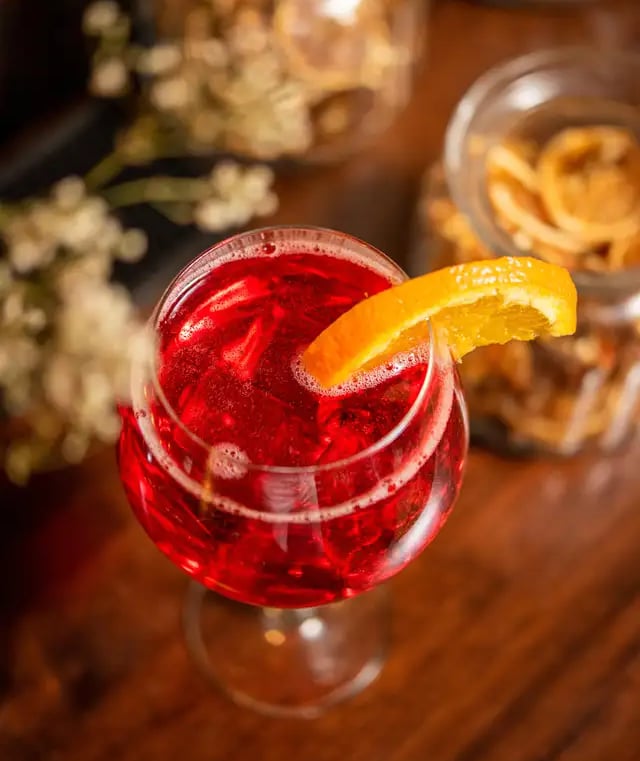 Un cocktail spritz avec un tranche d'orange sur un bar