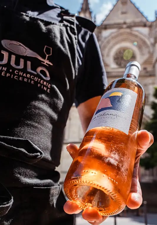 un homme tient une bouteille de vin rosée