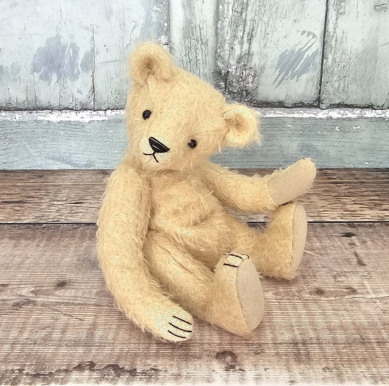 a little hand made teddy bear sitting on a table