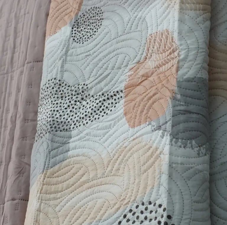 Muestras de colchas en frente de unas cortinas para enseñar los productos que se ofrecen.