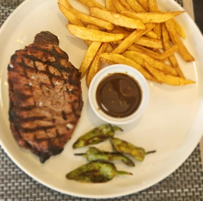 Grilled steak served with French fries and smoky barbecue sauce on a stylish wooden platter 