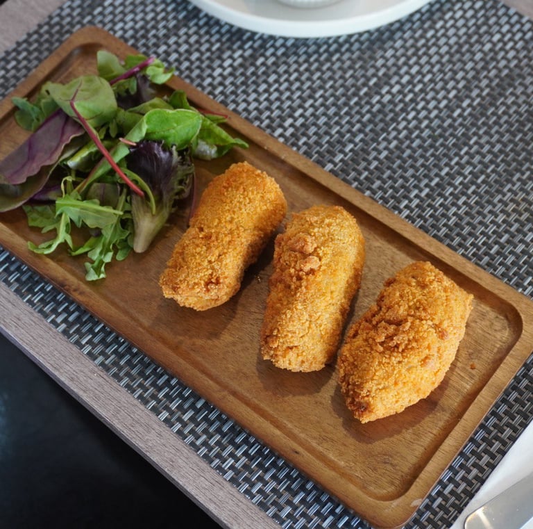 Close-up of crispy chicken croquettes served with mixed green salat.