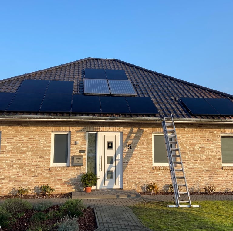 Residential brick house with solar panels installed on a dark tiled roof and a ladder against the gutter.