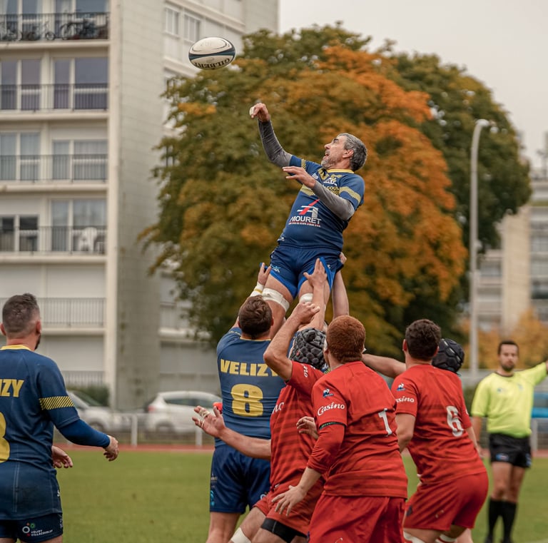 Joueur de rugby porté par ses coéquipiers pour récupérer une balle en touche