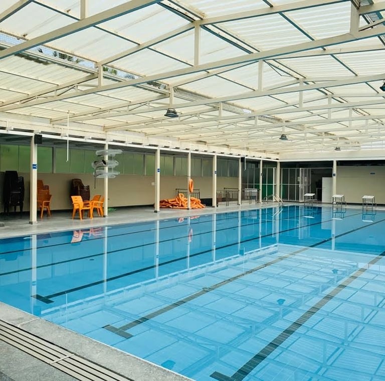 “Clean and spacious indoor swimming pool with seating and equipment around.” Group swimming lesson