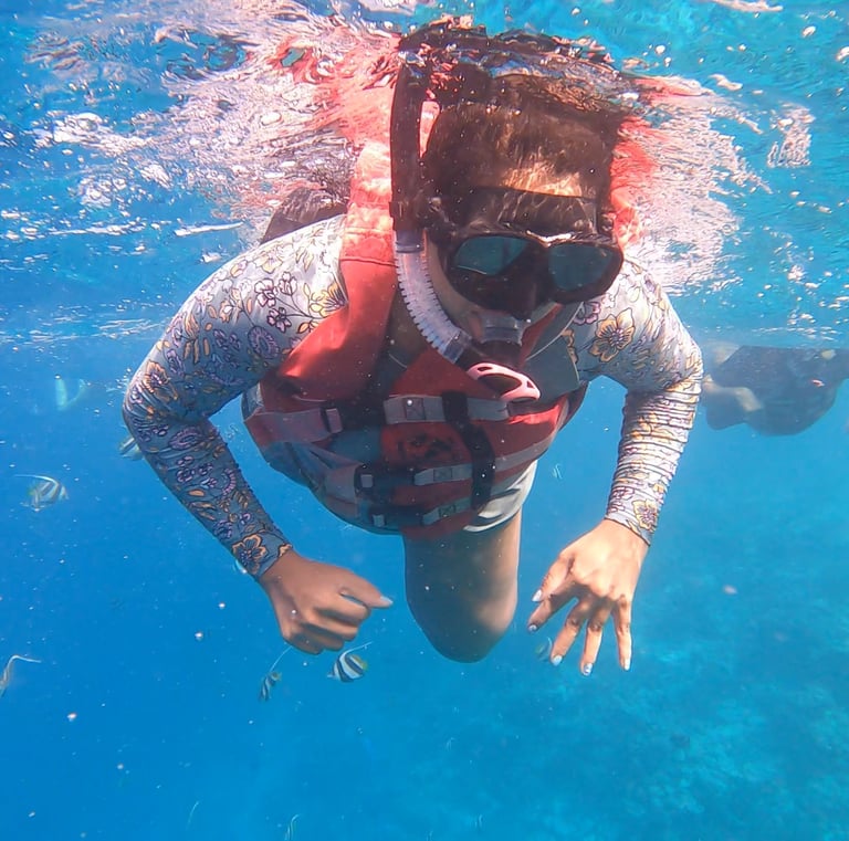 “Person wearing a snorkel mask and life jacket swimming underwater in a clear pool.”