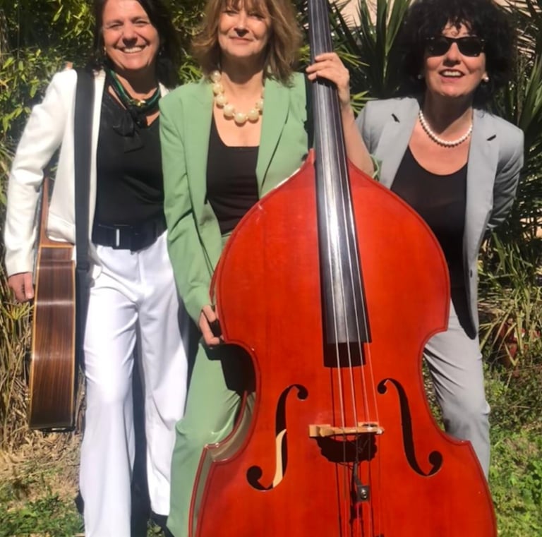 trois femmes en costume qui tiennent une guitare et une contrebasse