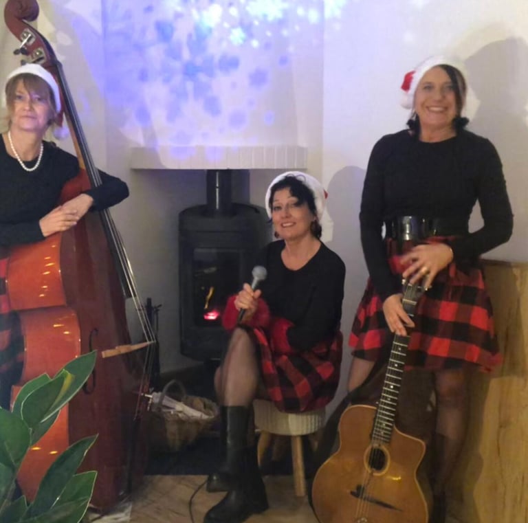 trois femmes en robe rouge et noire à carreaux autour d'une cheminée,une guitare et une contrebasse