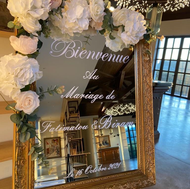 a sign board with flowers and a mirror