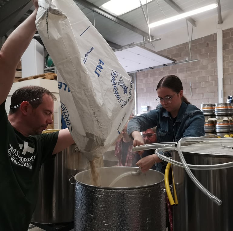 Brewer pouring malt into tank for a collaborative beer using pineapple weed