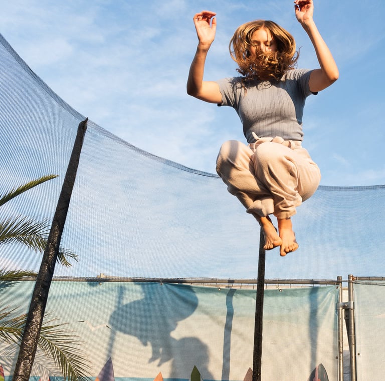Photo of a girl jumping on a trampoline in sunset light