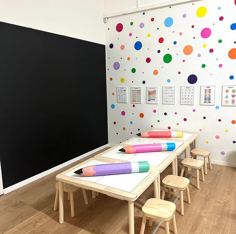 Lernbereich mit großen Stiften und Kindertischen – Vorbereitung auf den Schulstart in der Spielgrupp