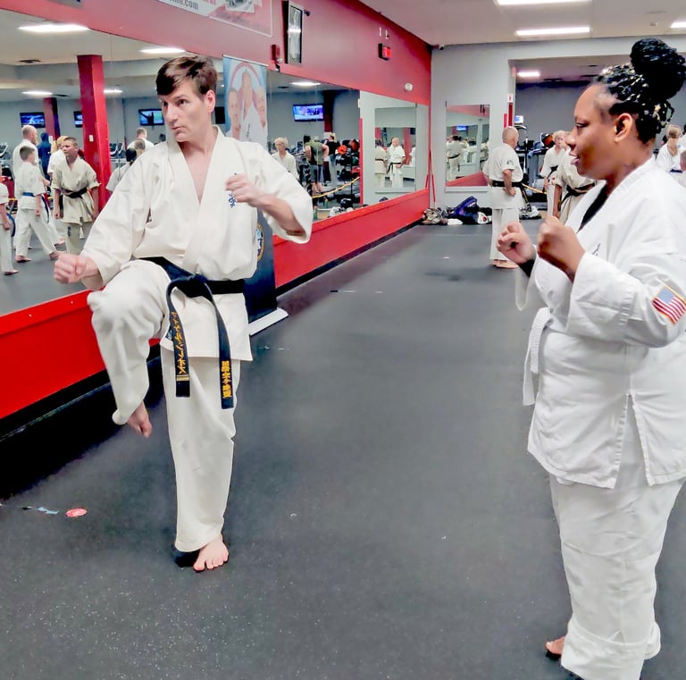 Sensei Mike Theiros demonstrating a kick to a white belt student at Kyokushin Karate USA in Rochester NY