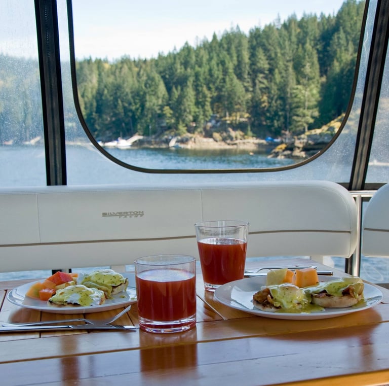 Gourmet eggs benedict breakfast served on a yacht with scenic forest and lake views.