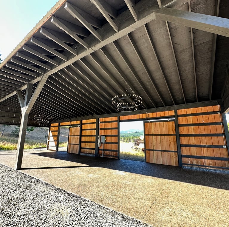 Rustic timber frame pavilion with open wood sliding doors and elegant chandelier lighting.