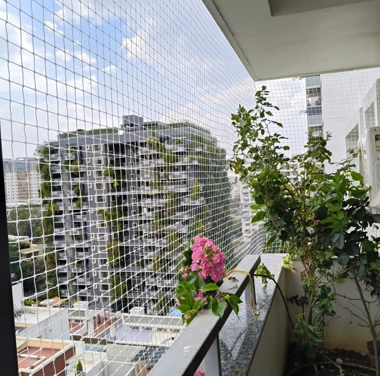 Installation team fitting a pigeon net on a balcony with cityscape in the background.