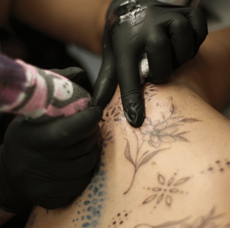 gros plans sur les mains d'Eva Ink vlr qui tatoue des pattern artistique dans le dos de sa cliente