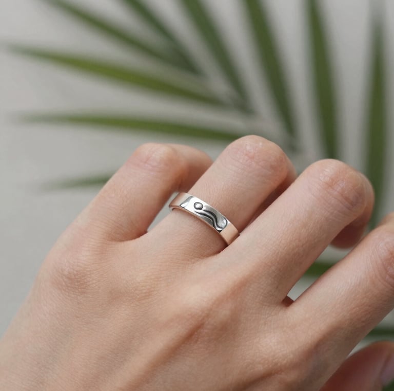 Close-up of a handcrafted silver ring resting on a smooth jade stone.