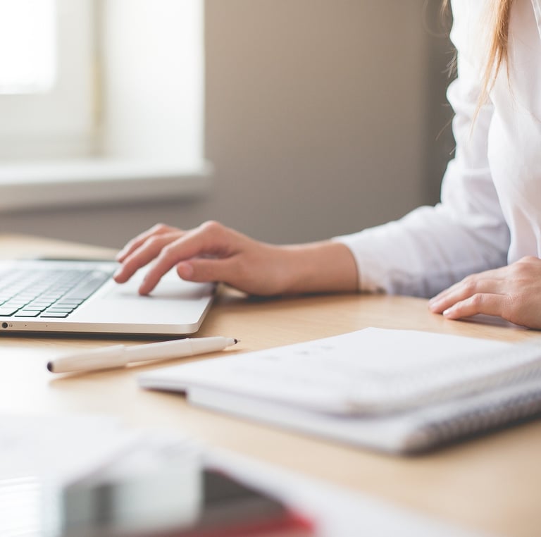 a woman sitting at a desk with a laptop and a notebook