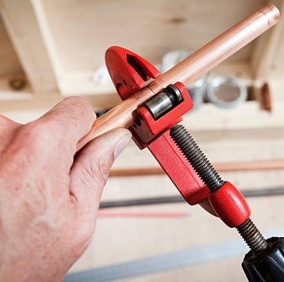 man cutting copper pipe