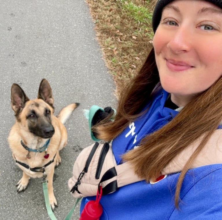 a woman in a blue jacket and hat with a dog on a leash