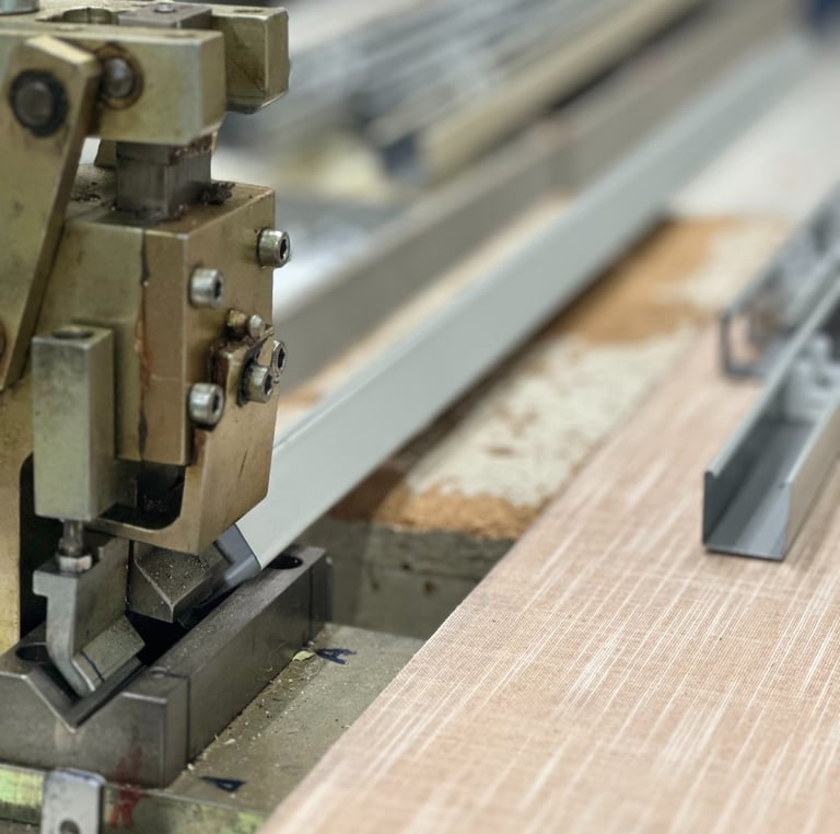 Industrial aluminum profile cutting machine processing metal frames in a factory workshop.