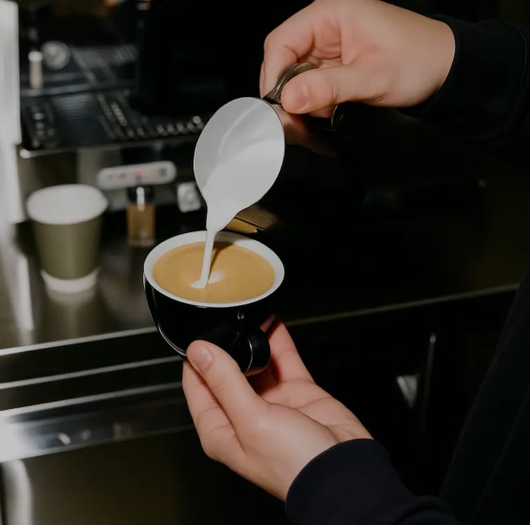 Barista preparando café espresso en taza negra con máquina de café de fondo