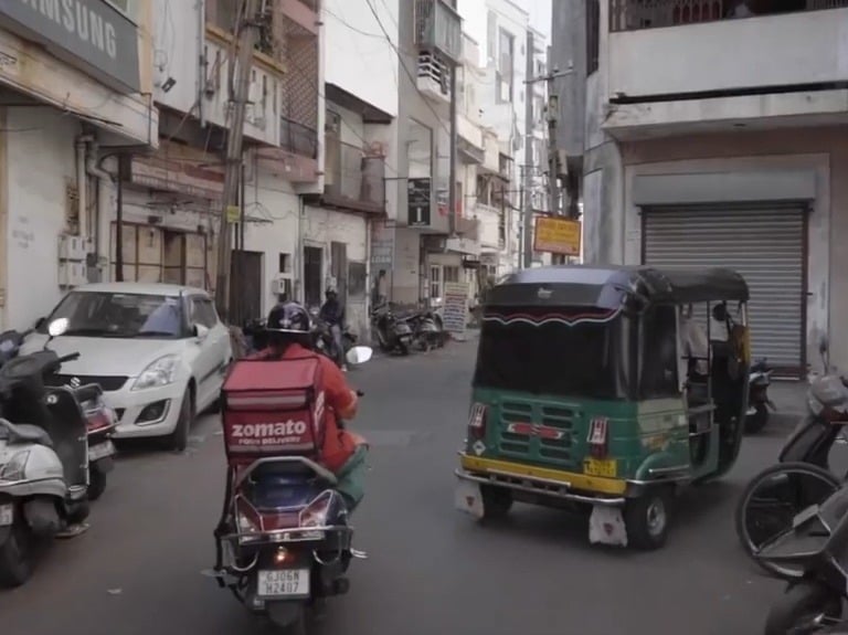 a zomato rider riding a motorcycle down a street