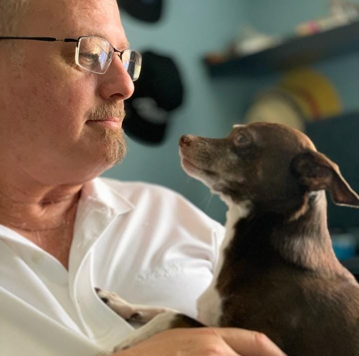 a man in a white shirt is holding a dog