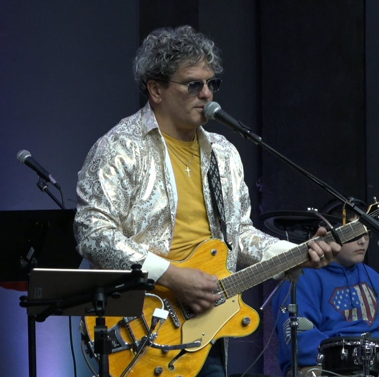 a man playing guitar and singing into a microphone