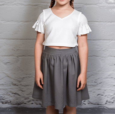 a young girl in a white top and gray skirtmade using PDF sewing patterns from LilRockyWear