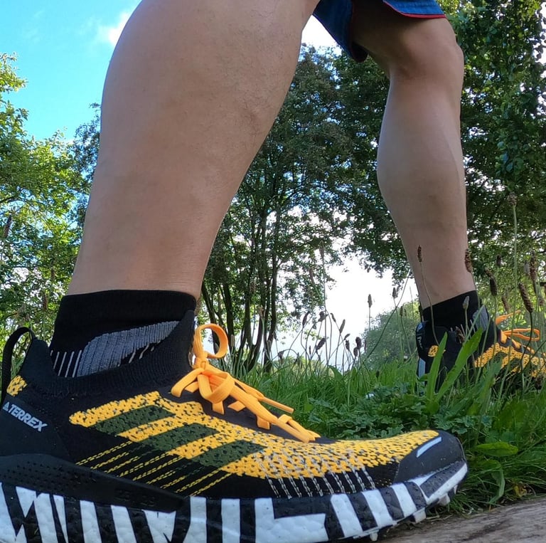 a person standing on a log in the woods weating adidas trainers