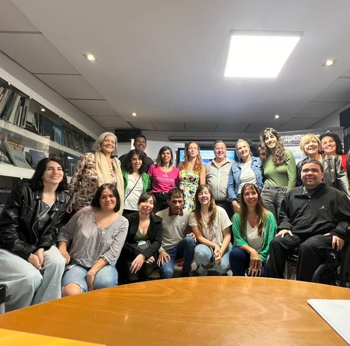 Grupo de personas sonrientes posando juntas en una sala durante una reunión sobre accesibilidad.