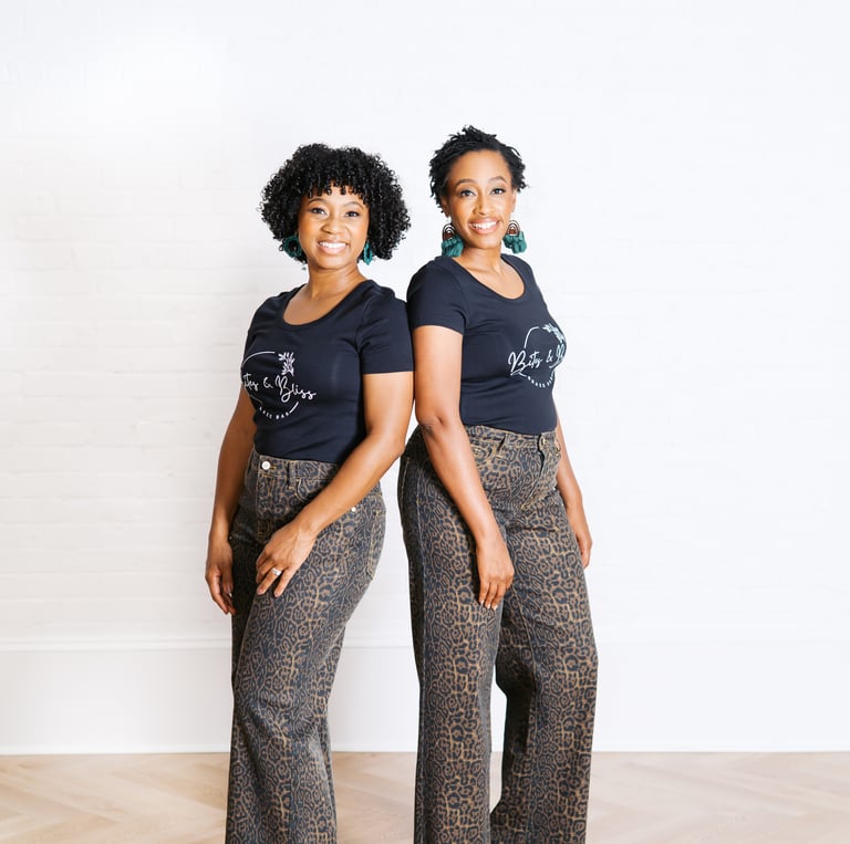 two women standing next to each other in front of a white wall