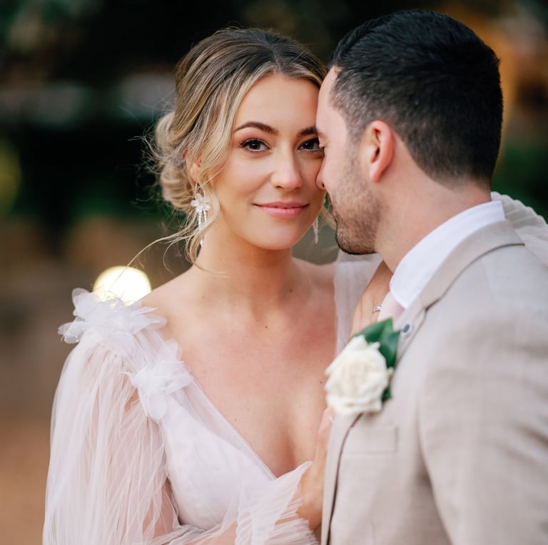 a bride and groom standing in front of a tree