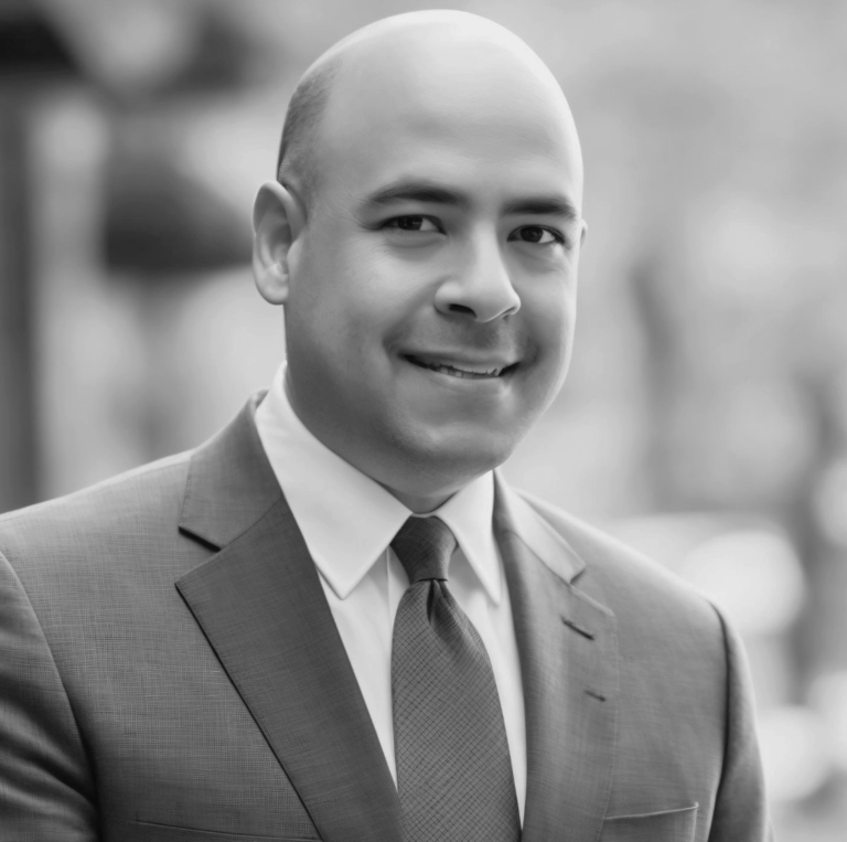 Black and white image of marketing expert, Deven Nongbri, in a suit, tie and button down shirt.