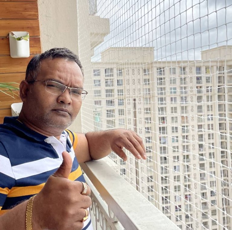 A happy customer standing beside their balcony secured with a neatly installed pigeon net by Arjilli
