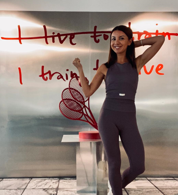 a woman in a gray top and leggings and a tennis racket