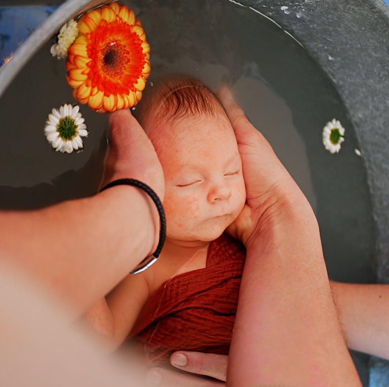 Un bébé portant un bob est tenu dans les bras d'une femme.