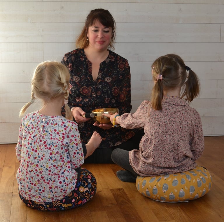 Une femme, Elodie Forget assise en face de deux petites filles pendant un cours de méditation