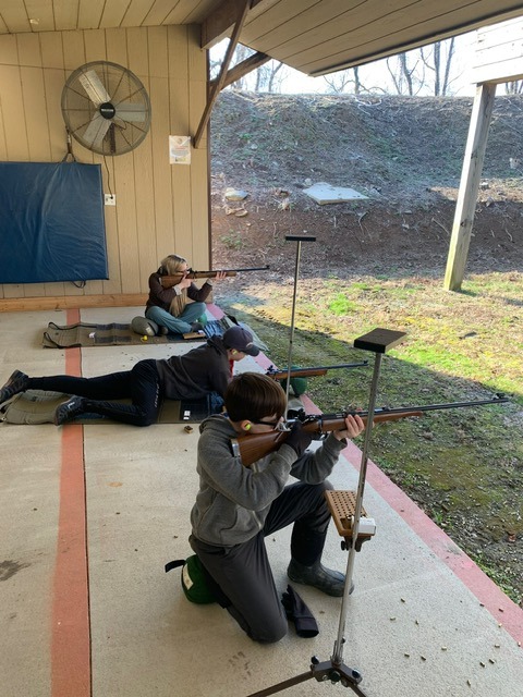 a man and woman are shooting rifles in a shooting range