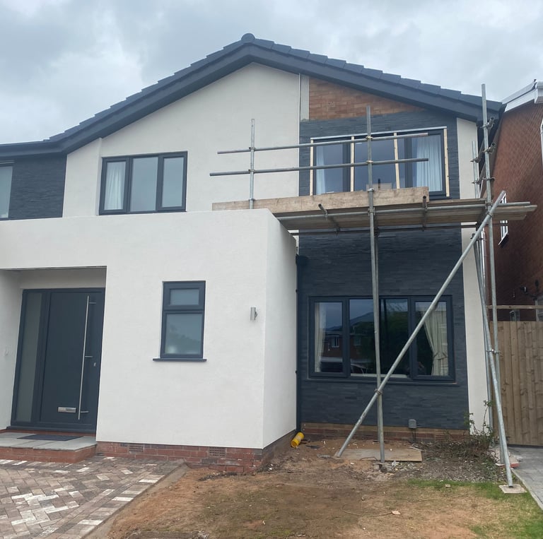 A partially rendered house with scaffolding against it.