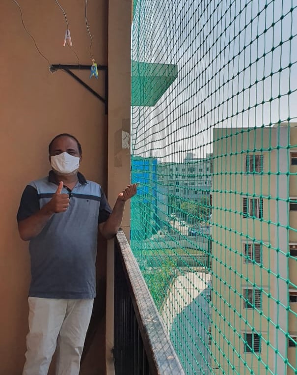 A close-up of a freshly installed white pigeon net covering a balcony in a Bangalore apartment.