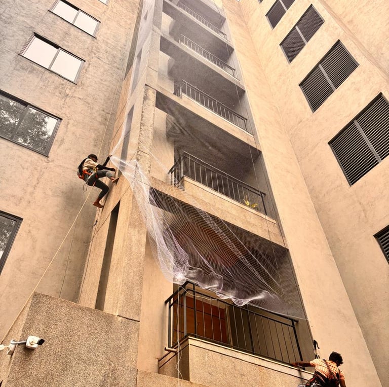 A technician carefully installing a durable pigeon safety net on a sunny apartment balcony overlooki