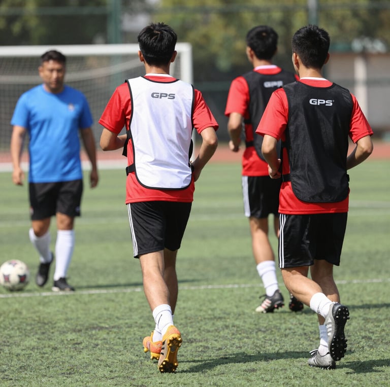 A dynamic football coach reviewing GPS tracker data with an athlete on the training pitch.