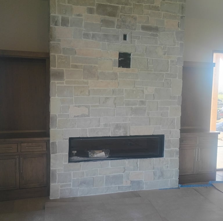 Modern floor-to-ceiling stone fireplace with a linear gas insert and built-in wood cabinets.