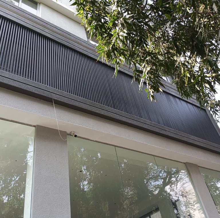 Modern building exterior with glass storefront windows and a decorative dark grey vertical louver panel.